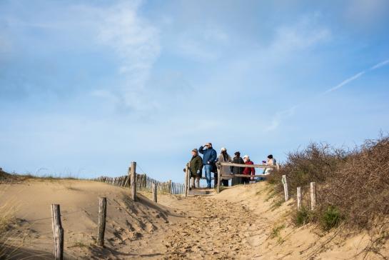 Groep mensen op een uitkijkplatform in de duinen